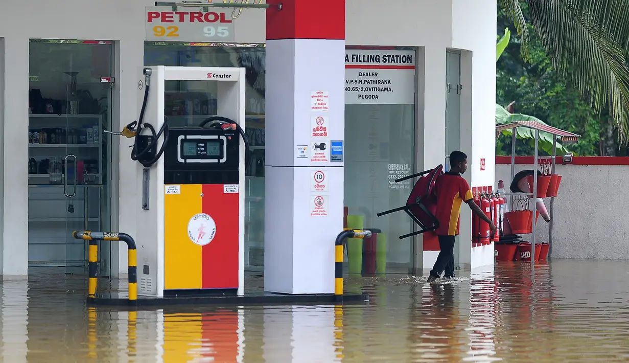 Seorang pekerja melewati halaman SPBU yang banjir akibat hujan lebat di Pugoda, Senin (16/5). Banjir dan tanah longsor yang melanda Sri Lanka memaksa puluhan ribu warga mengungsi dari rumah mereka, kata pejabat setempat. (Ishara S.KODIKARA/AFP)