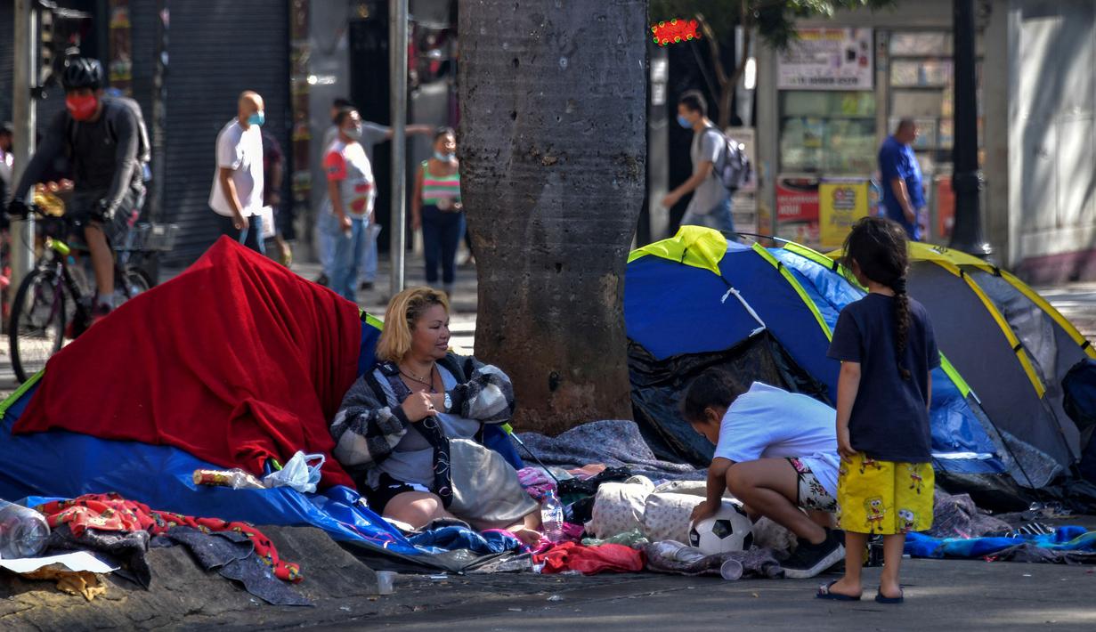 Sebuah keluarga tunawisma terlihat di Se Square, pusat kota Sao Paulo, Brasil, pada 19 Agustus 2021. Sao Paulo menghadapi krisis tunawisma, karena harga baru-baru ini menjadi beban yang terlalu berat bagi populasi yang semakin miskin. (NELSON ALMEIDA / AFP)