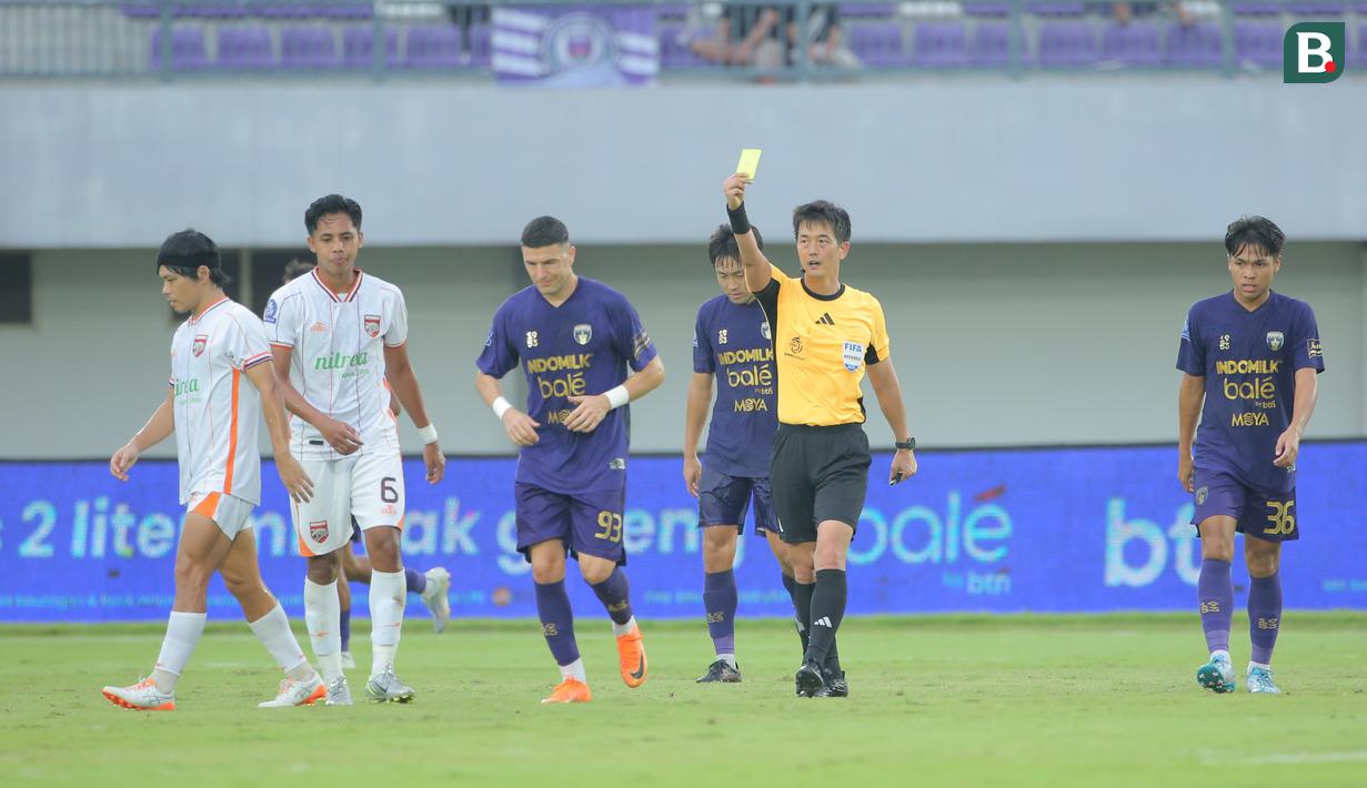 Wasit Ko Hyung-jin memberikan kartu kuning kepada pemain Borneo FC saat laga lanjutan BRI Super League 2025/2026 antara Persita melawan Borneo di Indonesia Arena, Tangerang, Banten, Jumat (09/01/2026). (Bola.com/Bagaskara Lazuardi)