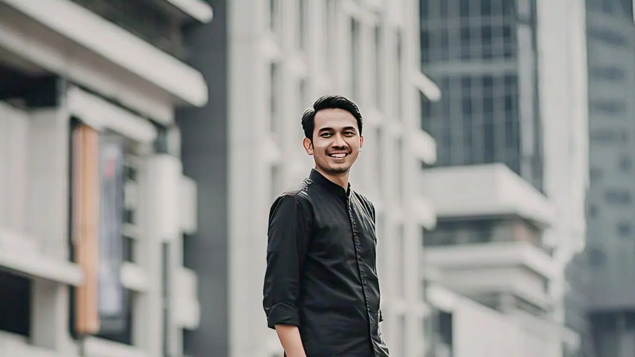 Model pria memakai kemeja hitam dengan celana abu tua /Meta AI