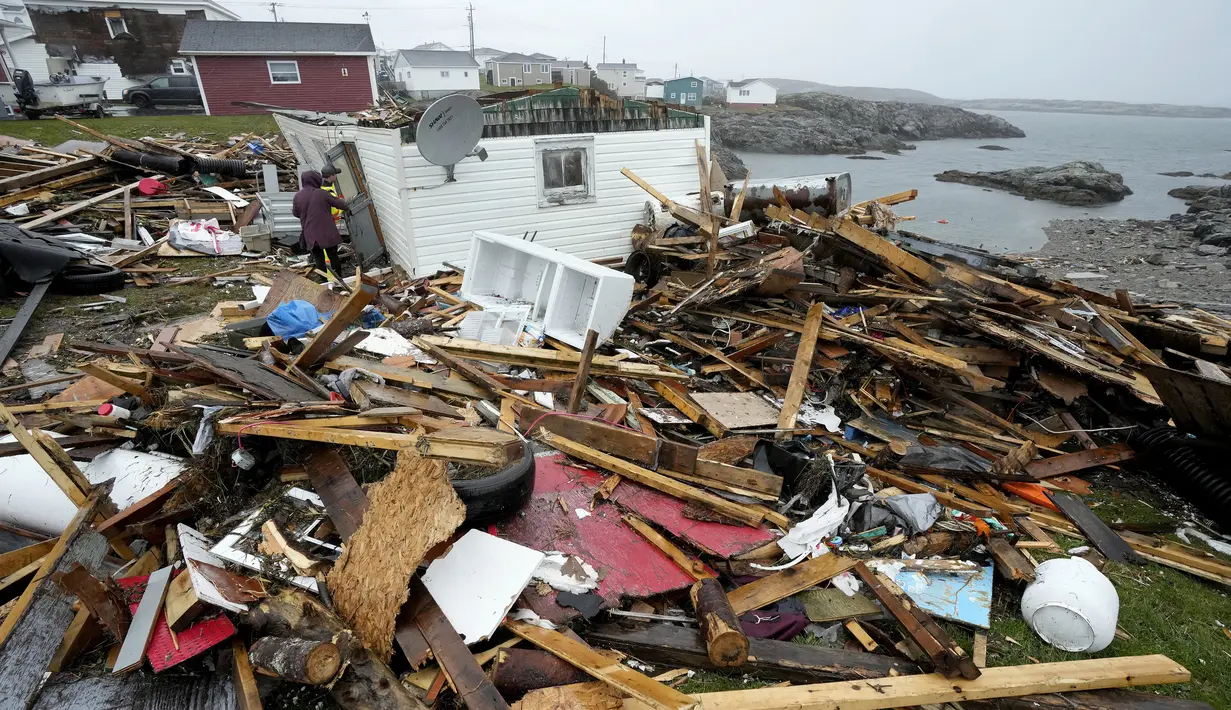 Seorang penduduk dan pekerja pencarian dan penyelamatan memeriksa sisa-sisa rumah yang hancur di Port aux Basques, Newfoundland dan Labrador, Senin, 26 September 2022. Di seberang Maritimes, Quebec timur dan di barat daya Newfoundland, dampak ekonomi dari murka badai Fiona adalah masih dihitung. (Frank Gunn/The Canadian Press via AP)