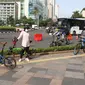 Seorang wanita berpose dengan sepedanya di kawasan Bundaran HI, Jakarta, Minggu (3/01/2021). Sejumlah aktivitas pesepeda melintasi jalan sudirman-thamrin di minggu pertama 2021, meski Car Free Day saat ini belum diberlakukan karena PSBB. (Liputan6.com/Herman Zakharia)
