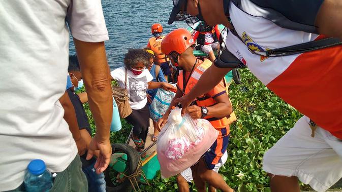 Keluarga dievakuasi ke tempat yang lebih aman di provinsi Camarines Sur, Filipina (31/10/2020). Otoritas Filipina memerintahkan satu juta orang di negara itu agar mengungsi dari rumah mereka. (Philippine Coast Guard via AP)