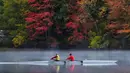 Sepasang pendayung meluncur di Sungai Androscoggin di Brunswick, Maine, tempat dedaunan berubah menjadi warna musim gugur, pada 10 Oktober 2021. Salah satu yang paling khas dari musim gugur adalah pohon-pohon yang berubah warna sebelum gugur. (AP Photo/Robert F. Bukaty)