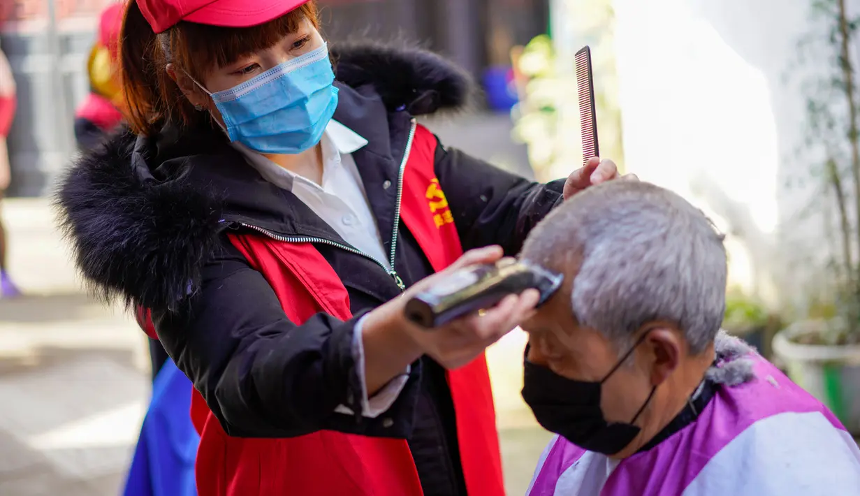 Barber sukarelawan (kiri) memotong rambut seorang pria di sebuah permukiman di Kota Chongqing, China barat daya, pada 16 Februari 2020. Permukiman di Distrik Beibei, Chongqing, mengoordinasikan tim barber sukarelawan untuk menyediakan jasa potong rambut gratis bagi penduduknya. (Xinhua/Liu Chan)