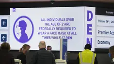 Peringatan elektronik menyarankan para pelancong tentang persyaratan untuk mengenakan masker di konter check-in United Airlines di terminal Bandara Internasional Denver di Denver (26/12/2021). Maskapai menunda ratusan penerbangan pada hari Minggu (26/12). (AP Photo/David Zalubowski)