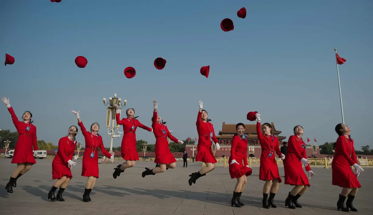 Para pemandu melemparkan topi mereka di lapangan Tiananmen selama sesi penutupan Kongres Partai Komunis ke-19 di Beijing (24/10). Sejumlah wanita cantik ini ditugaskan untuk memandu para peserta kongres. (AFP Photo/ Nicolas Asfouri)