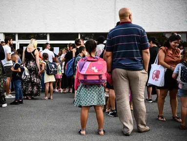 Anak-anak dan orang tua menunggu guru memanggil nama mereka pada hari pertama sekolah di sekolah dasar Condorcet di Lormont, di pinggiran Bordeaux, barat daya Prancis, Senin (4/9/2023). (Christophe ARCHAMBAULT / AFP)