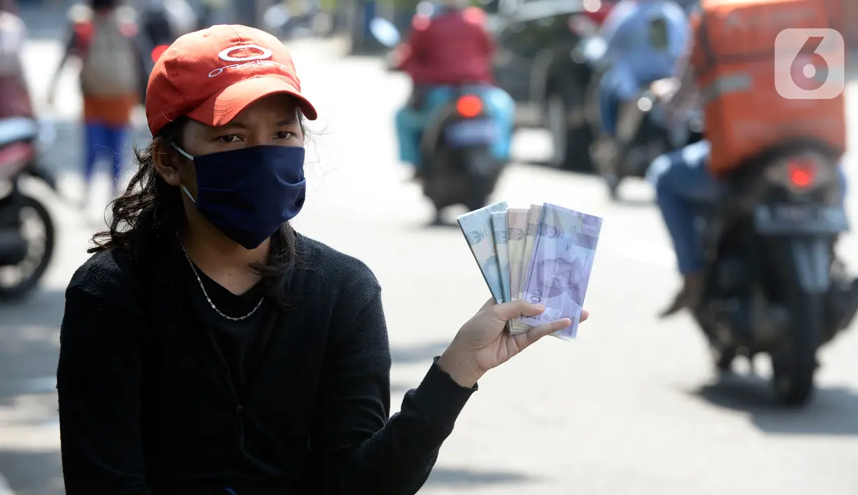 Penjual jasa penukaran uang menawarkan uang baru berbagai pecahan kepada pengguna jalan di kawasan Bintaro Sektor 2, Jakarta Selatan, Selasa (12/05/2020). Menjelang perayaan Lebaran, jasa penukar uang keliling yang berada di pinggir jalan-jalan utama mulai bermunculan. (merdeka.com/Dwi Narwoko)