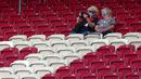 Dua orang penonton saat menyaksikan pertandingan antara  VfB Stuttgart melawan SC Freiburg pada laga Bundesliga, Sabtu (19/9/2020). Sejumlah liga di Eropa telah mengijinkan fans menonton langsung pertandingan di stadion. (AP Photo/Matthias Schrader)