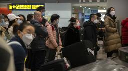 Pelancong yang memakai masker menunggu barang bawaan mereka di area kedatangan internasional di Bandara Internasional Ibukota Beijing di Beijing, Senin (9/1/2023). Pelancong internasional pertama tiba di China tanpa karantina wajib yang telah diberlakukan pada awal penerbangan. Pandemi tiga tahun lalu setelah pembatasan dicabut mulai hari Minggu. (AP/Mark Schiefelbein)