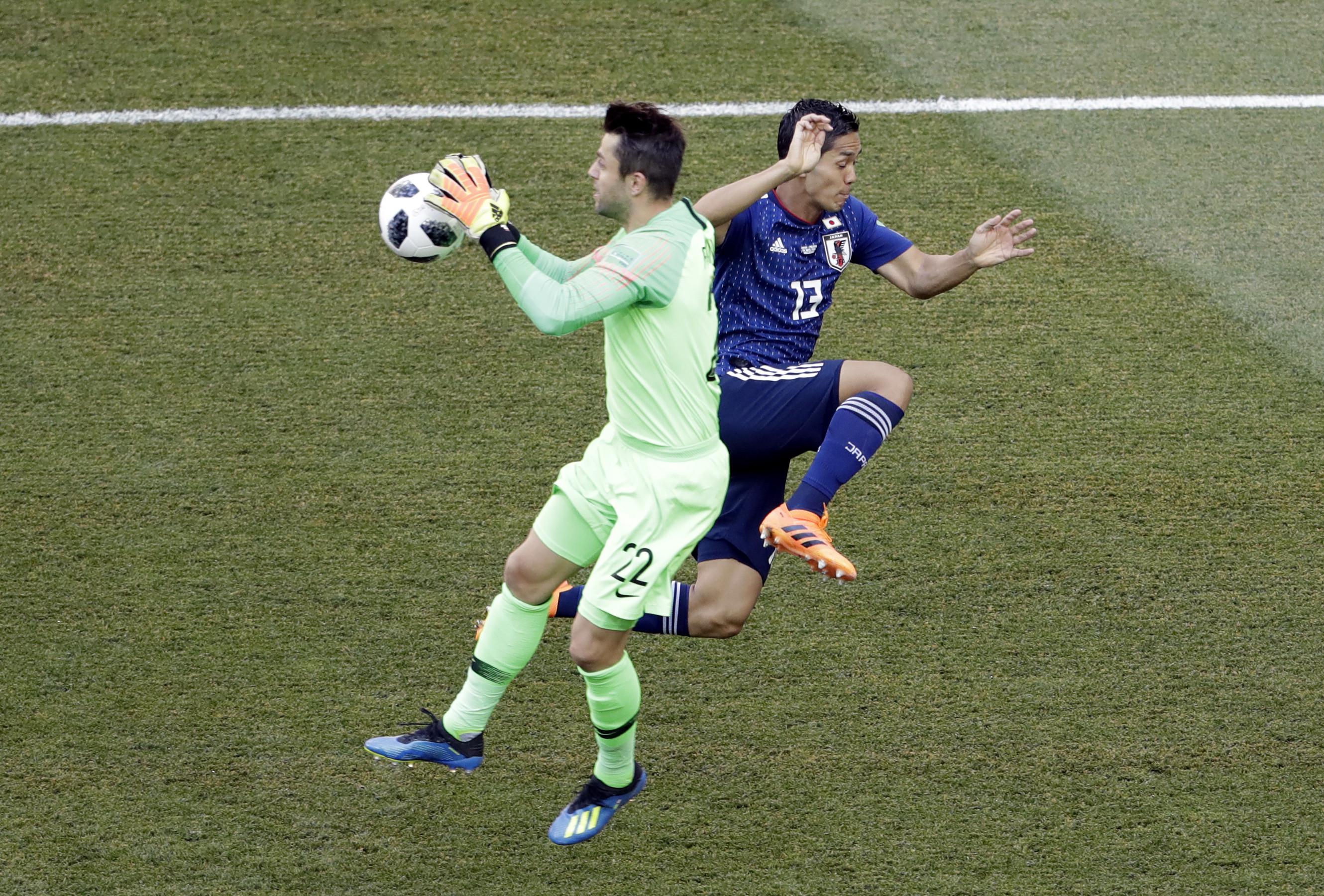 Kiper Polandia Lukasz Fabianski menangkap bola dengan striker Jepang Yoshinori Muto berusaha mengejar pada partai Grup H Piala Dunia 2018 di Volgograd Arena, Kamis (28/6/2018). (AP Photo/Themba Hadebe)
