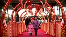 Dua orang anak melintas di sebuah jembatan bertema Imlek di sebuah pusat perbelanjaan kelas atas di Beijing (21/2). Jembatan berwarna merah yang bertema Imlek ini menjadi pusat perhatian dan tempat berfoto pengunjung. (AP Photo / Mark Schiefelbein)