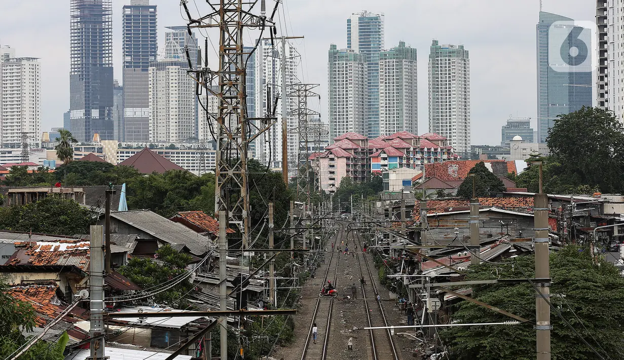 Warga beraktivitas di antara rel kereta dengan latar belakang gedung bertingkat di kawasan Pejompongan, Jakarta, Selasa (5/1/2021). Pemerintah mengalokasikan anggaran untuk PEN 2021 sebesar Rp403,9 triliun, anggaran ini naik dari rencana sebelumnya sebesar Rp372,3 triliun. (Liputan6.com/Johan Tallo)