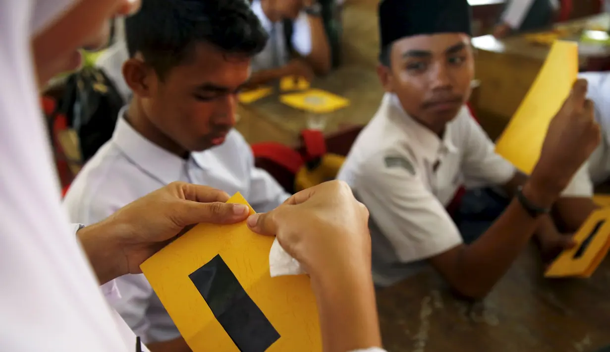 Pelajar merakit kacamata filter matahari buatan sendiri dalam workshop bersama Hong Kong Astronomical Society dan LAPAN di Ternate, (7/3). Kacamata ini akan digunakan untuk mengamati Gerhana Matahari Total. (REUTERS/Beawiharta)