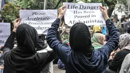 Pencari suaka asal Afghanistan membawa poster tuntutan di depan Kantor UNHCR, Jakarta, Senin (15/11/2021).  Ratusan pencari suaka tersebut menuntut segera dipindahkan ke negara ketiga yang terbebas dari konflik perang setelah lebih 10 tahun mengungsi di Indonesia. (merdeka.com/Iqbal S Nugroho)