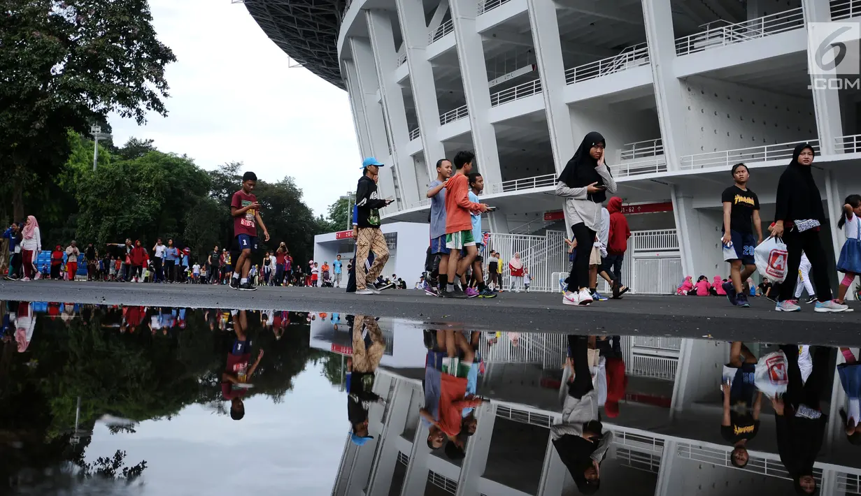 Warga berjalan santai melintasi kawasan lingkar luar Stadion Gelora Bung Karno (GBK), Jakarta, Minggu (21/1). Pascarenovasi, kawasan sekitar Stadion GBK kembali dipadati warga yang berolahraga. (Liputan6.com/Helmi Fithransyah)