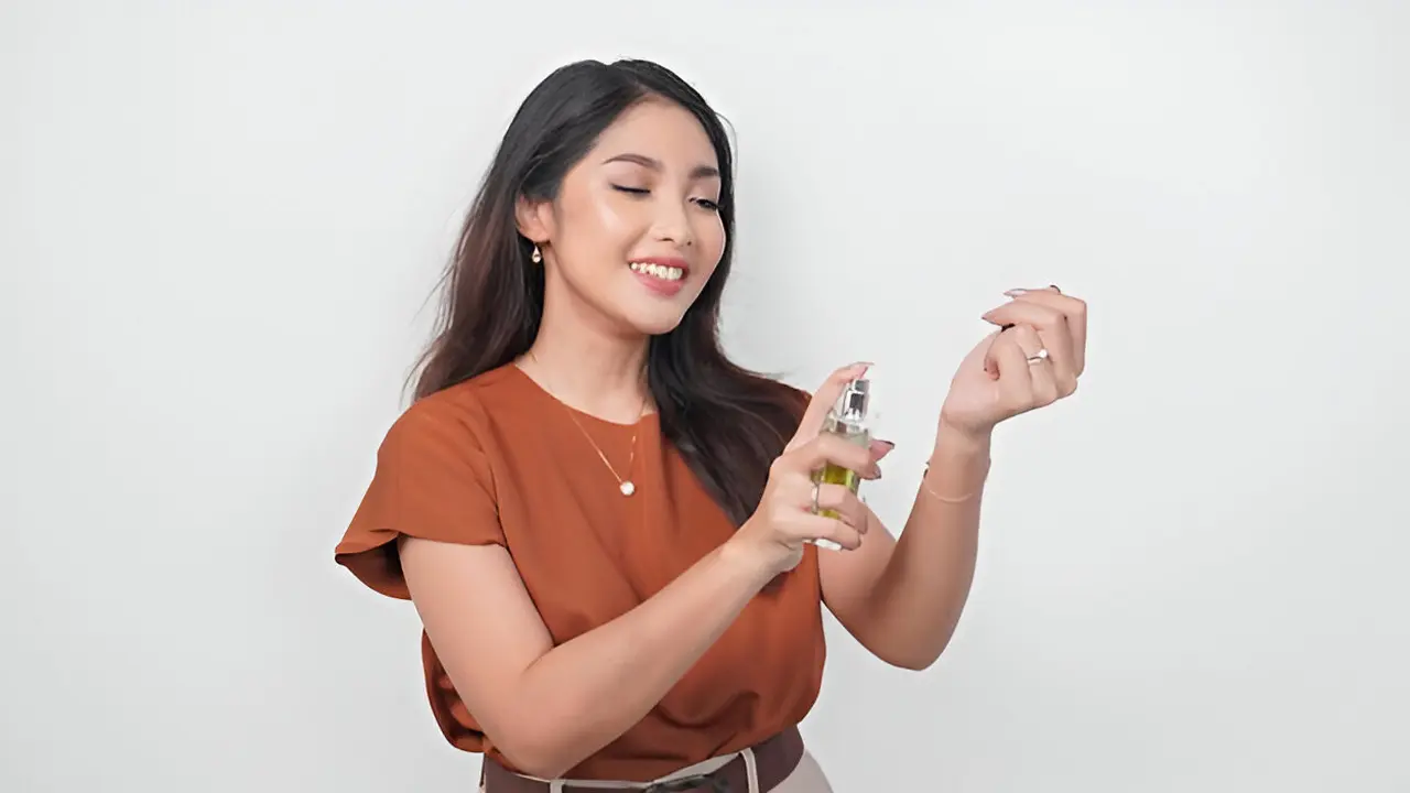 Seorang perempuan menyemprotkan parfum ke pergelangan tangannya (Foto Dok: Freepik/reezky11)