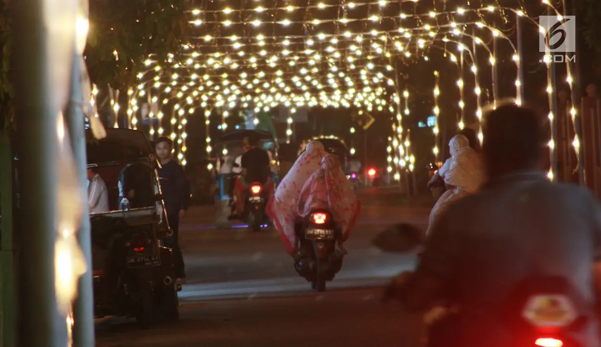 Pengendara sepeda motor melewati lampu minyak saat perayaan tumbilotohe atau penyalaan berjuta lampu minyak di akhir Ramadan di Kota Gorontalo, Jumat (31/5/2019). Tradisi ini diselenggarakan jelang Hari Raya Idul Fitri. (Liputan6.com/Arfandi Ibrahim)