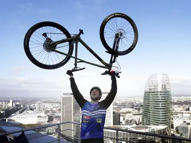 Pembalap sepeda asal Prancis, Aurelien Fontenoy, melakukan selebrasi usai berhasil mendaki 768 anak tangga dari 33 lantai gedung Trinity Tower di distrik La Defense, Paris, (17/1/2021). (AP/Christophe Ena)