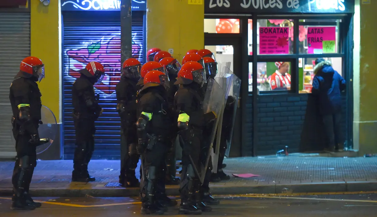 Polisi antihuru hara berjaga saat bentrok antara suporter Athletic Bilbao dan Spartak Moskow di Stadion San Mames, Bilbao, Spanyol, Kamis (22/2). Akibat bentrok tersebut seorang polisi meninggal. (AP Photo/Alvaro Barrientos)