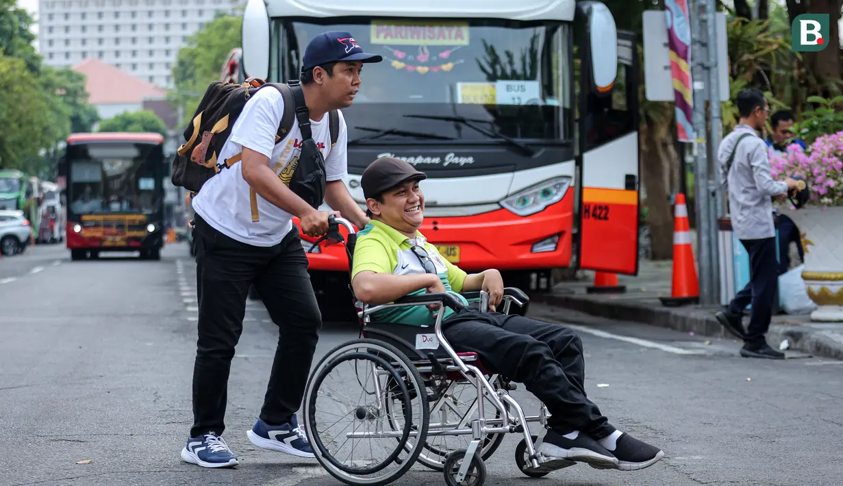 <p>Seorang suporter berkebutuhan khusus dibantu rekannya menyeberangi jalan untuk menaiki shuttle bus penonton dari titik lokasi Balai Kota Surabaya menuju Stadion Gelora Bung Tomo untuk menyaksikan pembukaan Piala Dunia U-17 2023 sekaligus laga Timnas Indonesia U-17 menghadapi Ekuador, Jumat (10/11/2023). (Bola.com/Bagaskara Lazuardi)</p>