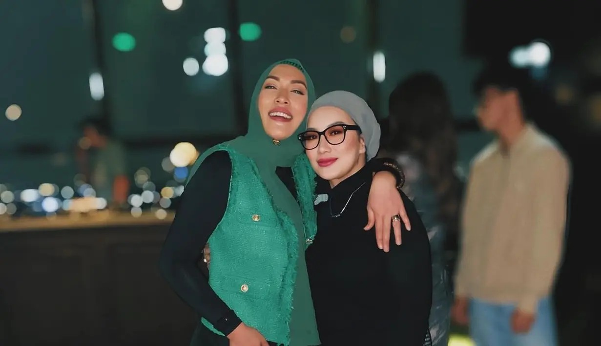 Tampak keakraban Reza Artamevia dan Angelina Sondakh yang kompak kenakan kerudung nuansa kehijauan. Reza memadukannya dengan long sleeve top hitam dan checkered long pants. Sedangkan Angelina dengan inner hitam dan vest hijau.  [@angelinasondakh09].