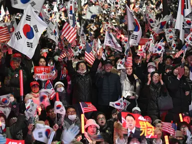Para pendukung Yoon Suk Yeol melambaikan bendera Korea Selatan dan Amerika Serikat dalam sebuah unjuk rasa di dekat kediaman presiden di Seoul pada tanggal 8 Maret 2025, setelah iring-iringan mobil yang membawa Yoon tiba di kediaman tersebut. (Jung Yeon-je/AFP)