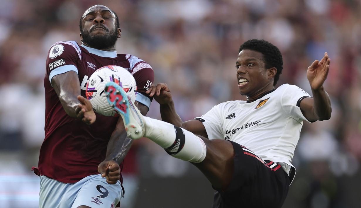 Pemain West Ham, Michail Antonio (kiri), berusaha mengontrol bola dan melewati pemain MU, Tyrell Malacia, dalam laga pekan ke-35 Premier League 2022/2023 yang berlangsung di London Stadium, Senin (8/5/2023) dini hari. (AP Photo/Ian Walton)