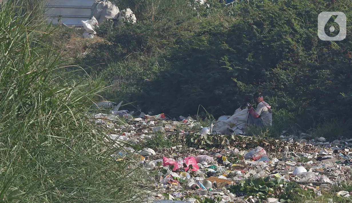 Seorang pria terlihat di antara sampah yang menumpuk di aliran kali Kampung Bogor, Desa Setiasih, Tarumajaya, Kabupaten Bekasi, Rabu (30/9/2020). Tumpukan sampah itu akibat kurangnya kesadaran masyarakat untuk tidak membuang sampah sembarangan khususnya di aliran kali. (Liputan6.com/Herman Zakharia)