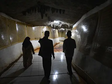 Pengunjung berjalan sambil mengamati ayat-ayat Al Quran yang ditempel pada dinding Gua di Desa Cinangneng, Tenjolaya, Kabupaten Bogor, Jawa Barat, Selasa (11/3/2025). (merdeka.com/Arie Basuki)