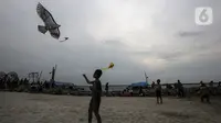 Pengunjung bermain layangan di Pantai Karnaval Ancol, Jakarta, Jumat (14/5/2021). Ancol dibuka khusus bagi warga ber-KTP DKI Jakarta dan membatasi jumlah wisatawan dengan kapasitas 30 persen. (Liputan6.com/Johan Tallo)