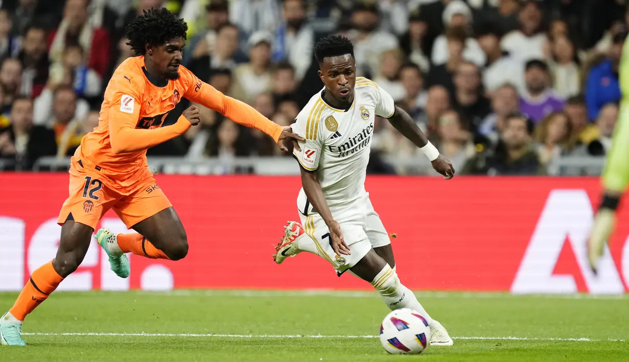 Pemain Real Madrid, Vinicius Junior, berusaha melewati pemain Valencia, Thierry Correia, pada laga Liga Spanyol di Stadion Santiago Bernabeu, Sabtu (11/11/2023). (AP Photo/Jose Breton)