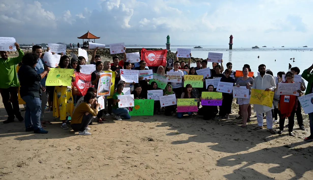 Massa mengangkat plakat saat kampanye perubahan iklim global di Pantai Sanur, Bali, Jumat (20/9/2019). Kampanye ini menuntut tindakan yang lebih cepat untuk mengatasi perubahan iklim global. (SONNY TUMBELAKA/AFP)
