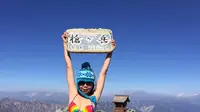 Gigi Wu terlihat mengangkat papan bertuliskan Gunung Yarigatake sambil memakai bikini. (dok. Facebook: Remembering Gigi Wu/Esther Novita Inochi)