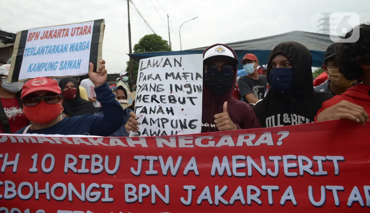 Warga Kampung Sawah membentangkan spanduk saat melakukan aksi dengan menutup akses jalan Cakung Cilincing, Jakarta, Rabu (18/11/2020). Aksi tutup jalan ini bentuk protes warga atas hak tanahnya yang terkena proyek pembangunan jalan tol Cakung Cilincing (Cacing)-Cibitung. (merdeka.com/Imam Buhori)