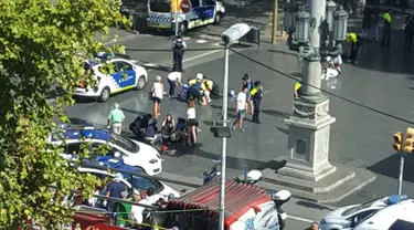 Petugas dibantu warga membantu korban setelah mobil van menabrak kerumunan orang  di Jalanan Las Ramblas, Barcelona, Spanyol (17/8). Lebih dari 50 orang dilaporkan luka-luka dan 13 orang tewas akibat kejadian tersebut. (Daniel Vil via AP)