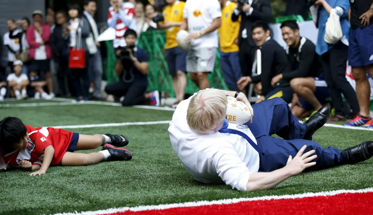 Walikota London Boris Johnson (kanan) terjatuh selama bermain rugby dengan anak - anak di sebuah lapangan mini, Tokyo, Jepang,  Kamis (15/10/2015).  Acara ini dihadiri para organisasi masyarakat dan perwakilan dari rugby Jepang. (REUTERS/Issei Kato) 