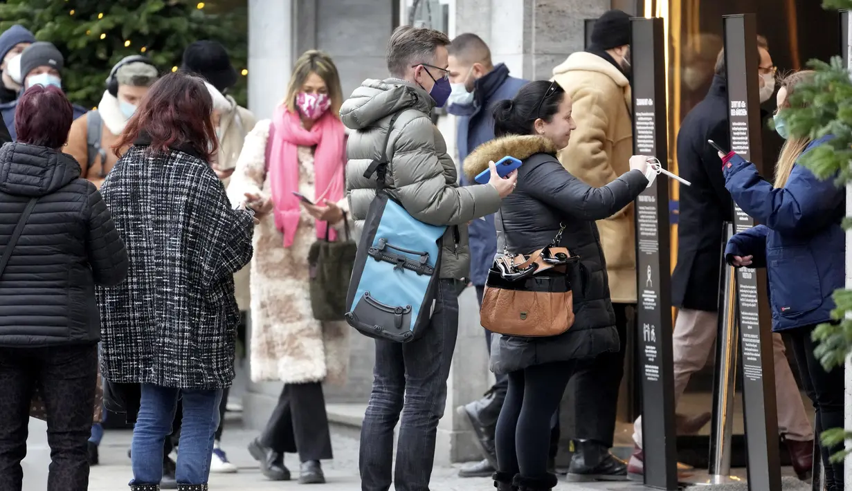 Orang-orang menunjukkan status vaksinasi mereka saat antre di depan department store terkenal 'KaDeWe' (Department Store Of The West) di Berlin, Selasa (21/12/2021). Jerman akan memperkenalkan langkah-langkah baru untuk mengekang penyebaran COVID-19 sebelum Malam Tahun Baru. (AP Photo/Michael Sohn)