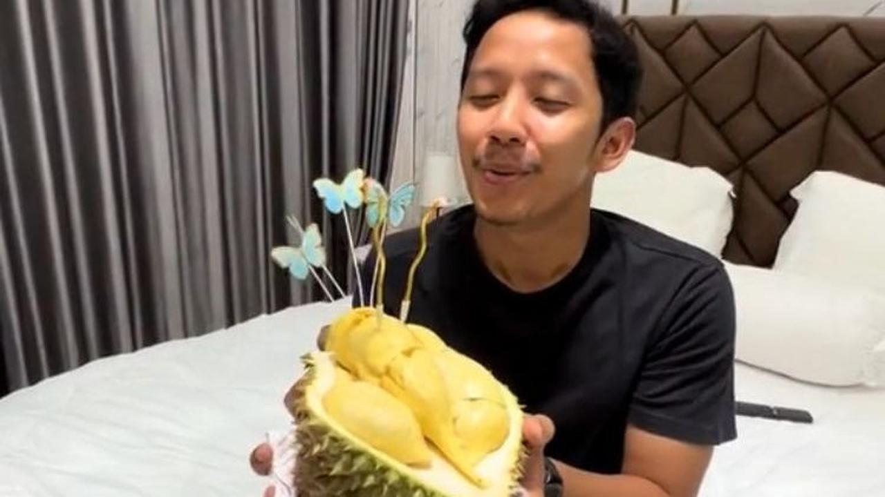 Selanjutnya, sang suami mengambil 'kue' ulang tahun durian ini dan meniup lilin.