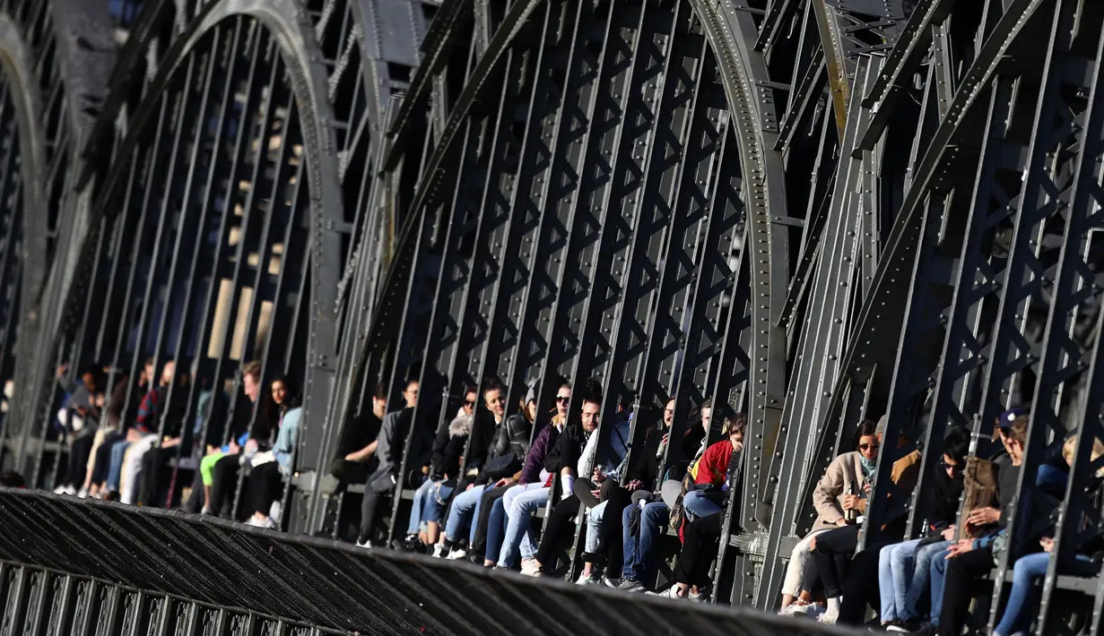 Kaum muda menikmati matahari terbenam di jembatan 'Hackerbruecke' di Munich, Jerman, Minggu, (28/3/2021). Enam lengkungan besi, lebar 28,8 meter dan tinggi delapan meter, menopang jalan sepasang pilar batu menopang lengkungan di jembatan tersebut. (AP Photo/Matthias Schrader)