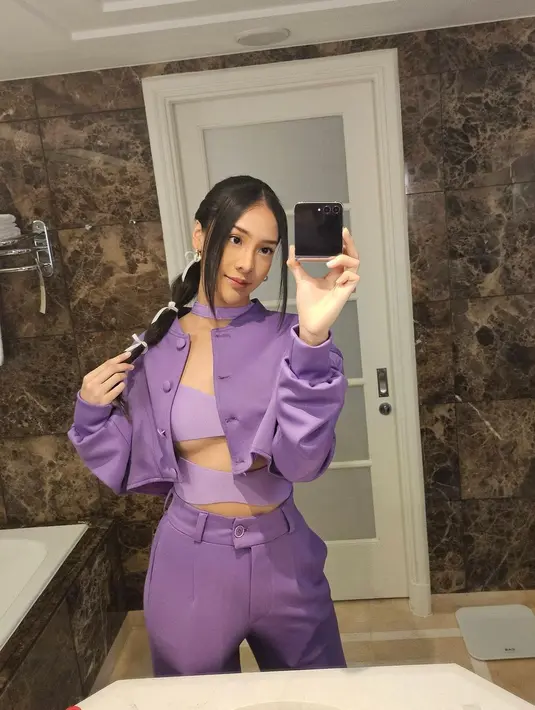 Ia mengenakan cutout top berlapis blazer dan cutbray pants berwarna ungu serta sneakers [@anyageraldine]