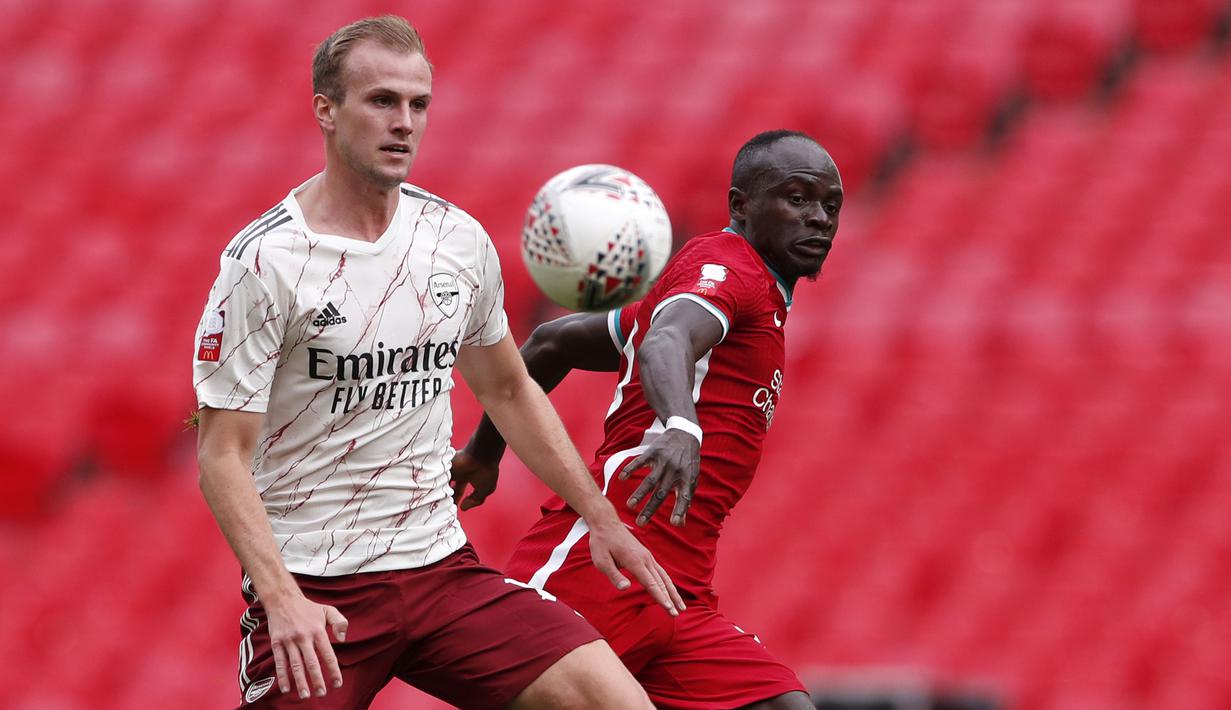 Bek Arsenal, Rob Holding, berebut bola dengan penyerang Liverpool, Sadio Mane, pada laga Community Shield 2020 di Stadion Wembley, Sabtu (29/8/2020) malam WIB. Arsenal menang 5-4 atas Liverpool lewat adu penalti. (Andrew Couldridge/Pool via AP)