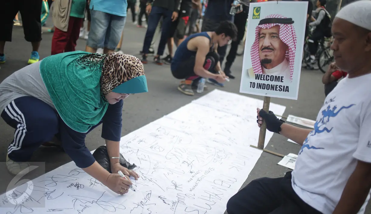 Pengunjung Car Free Day (CFD) menandatangani spanduk berisi petisi mendukung kedatangan Raja Salman, di Bundaran HI, Jakarta, Minggu (26/2). Petisi berisi harapan atas  kunjungan Raja Arab Saudi, Salman bin Abdulazis Al Saud. (Liputan6.com/Faizal Fanani)