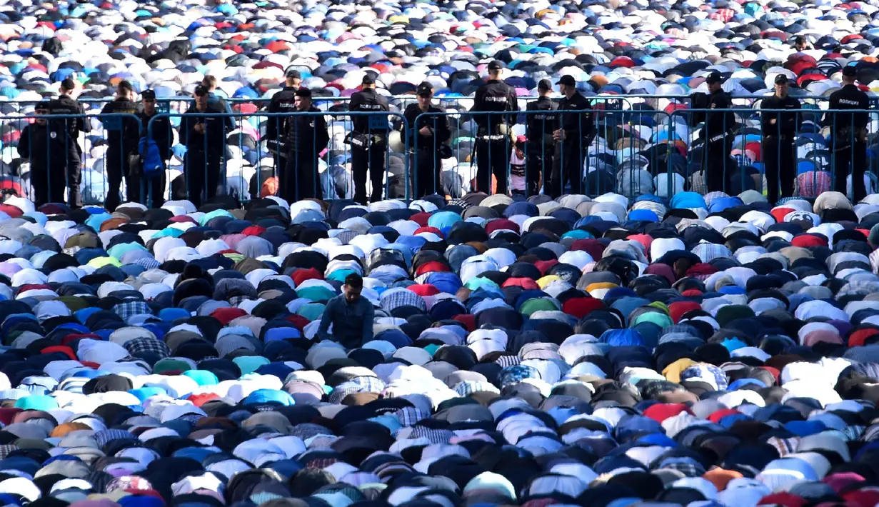 Sejumlah petugas kepolisian berjaga saat umat muslim Rusia melaksanakan salat Idul Fitri di luar masjid di pusat kota Moskow, Selasa (5/7). Perayaan Idul Fitri 1437 H di Rusia jatuh pada hari ini. (Kirill KUDRYAVTSEV/AFP)