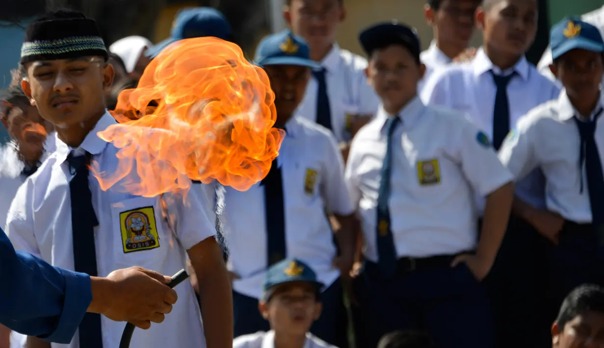Para siswa menyaksikan petugas pemadam kebakaran memeragakan cara memadamkan api, Banda Aceh, Senin (11/11/2019). Para pelajar melihat, mempelajari, dan mendapatkan praktik langsung penanganan kebakaran yang disebabkan kompor gas juga cara pemadaman dengan racun api. (CHAIDEER MAHYUDDIN/AFP)