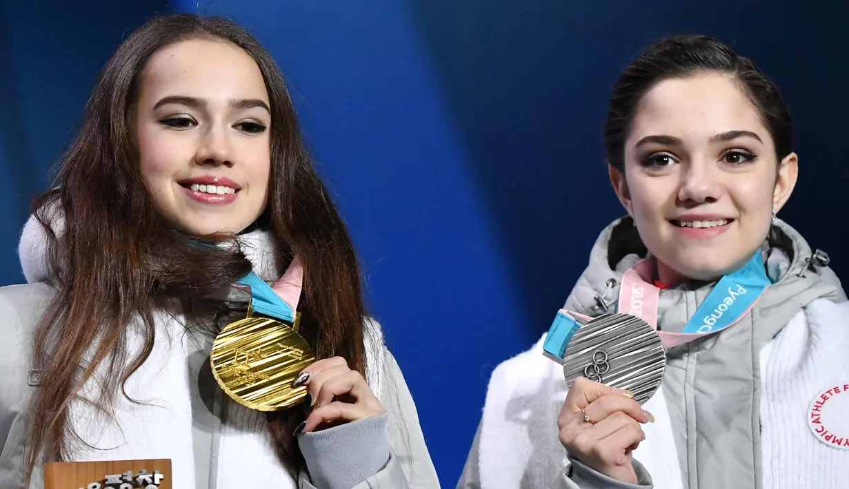 Alina Zagitova (kiri) dan Evgenia Medvedeva dari Rusia tersenyum di atas podium usai pertandingan figure skating putri Olimpiade Musim Dingin Pyeongchang 2018 di Pyeongchang Medals Plaza (23/2). (AFP Photo/Dimitar Dilkoff)