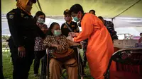 Seorang warga menerima vaksin virus corona COVID-19 Sinovac di pusat vaksinasi massal darurat di lapangan sepak bola di Surabaya, Jawa Timur, Kamis (30/9/2021). Vaksinasi ini dalam rangka percepatan penanganan COVID-19 dan pemulihan ekonomi nasional. (Juni Kriswanto/AFP)