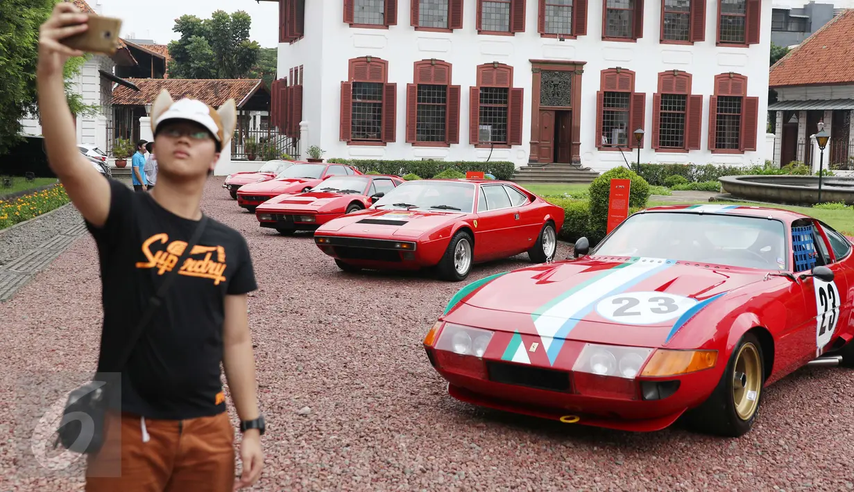 Pengunjung berfoto dengan latar belakang Ferrari klasik di Gedung Arsip Nasional, Jakarta, Selasa (14/3). Merayakan ulang tahun ke-70 keberadaan Ferrari di dunia otomotif, Ferrari Jakarta memboyong 10 supercar klasik pilihan. (Liputan6.com/Angga Yuniar)