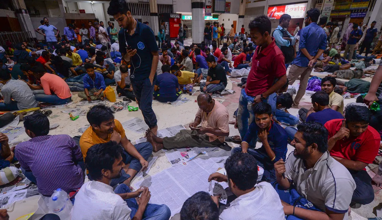 Orang-orang Bangladesh bermain kartu sambil menunggu dalam antrean untuk mendapatkan tiket  mudik lebaran di Stasiun Kereta Kamalapur, Dhaka, Kamis (23/5/2019). Pemudik Bangladesh rela antre berjam-jam dan bahkan menunggu jauh hari sebelum pembukaan loket tiket. (MUNIR UZ ZAMAN/AFP)